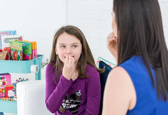 Child practicing communication skills with a speech therapist in a therapy session.
