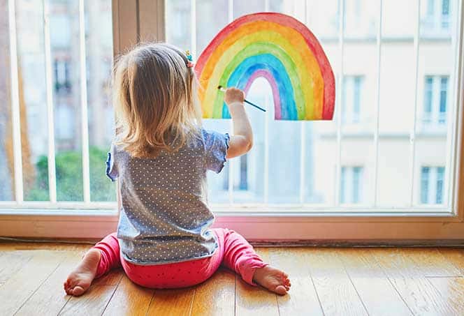 Rainbow drawing on a window by a young child for communication and creativity.