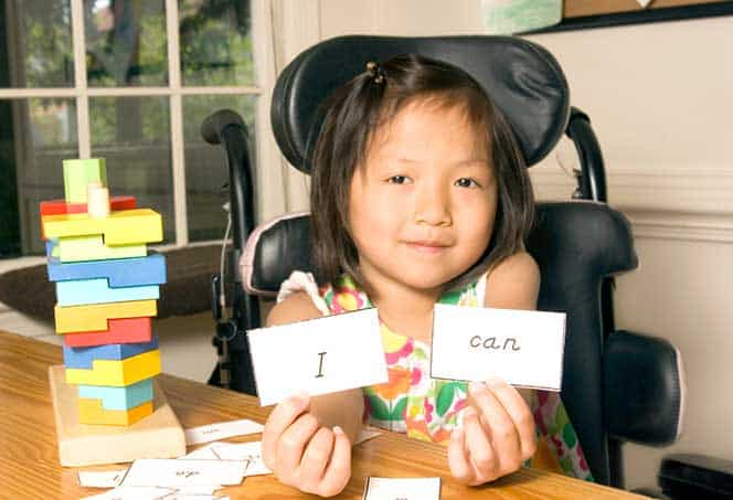 Young girl with communication cards and stacking blocks, promoting speech therapy and language learn.