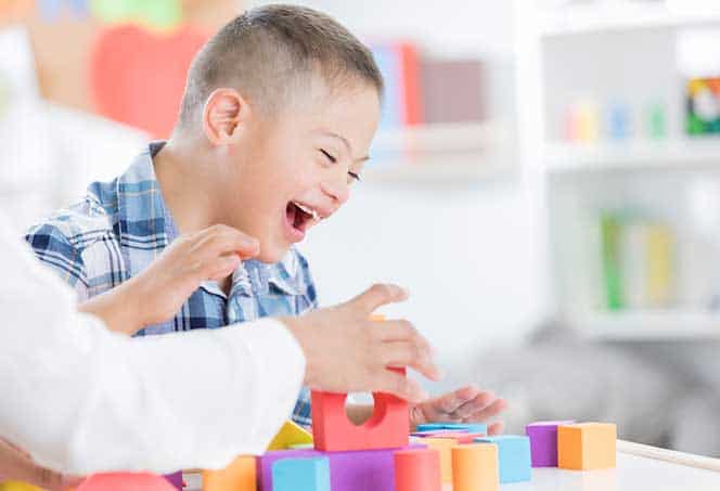 Child engaging in speech therapy activities with colorful blocks at All About Communication.