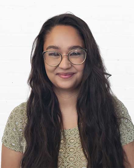 Young woman with glasses smiling, demonstrating effective communication skills.
