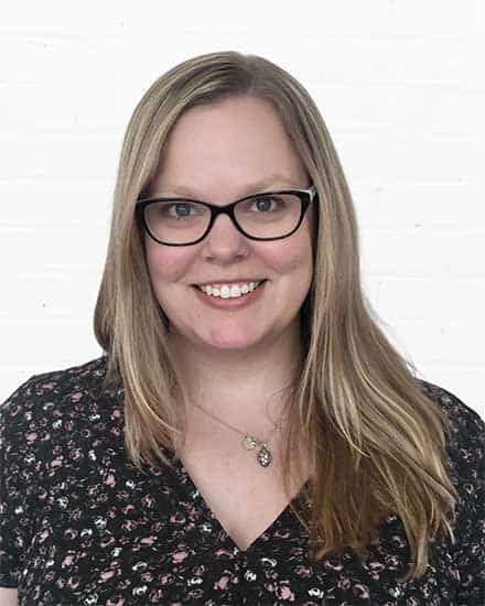 Professional woman with glasses smiling, representing communication expert.