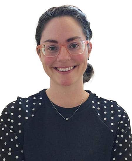 Woman smiling, wearing glasses, black polka dot top, promoting communication skills.
